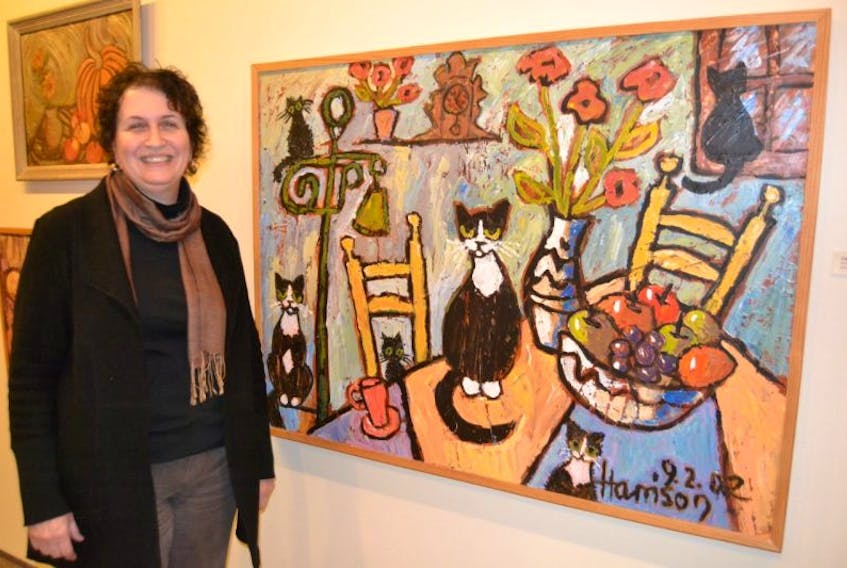 Paula Kenny, co-curator, shows Cats in the Kitchen. It’s one of the many pieces in Elaine Harrison’s retrospective exhibition on display at Eptek Centre in Summerside until May 8.