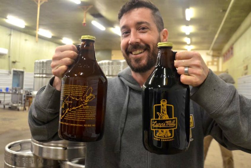 Mark Reid holds up a couple of growlers of Lunn’s Mill Beer Company product during opening day of the new Lawrencetown brewery on March 2. He’s partners with Sean Ebert, Chantelle Webb, and Chad Graves.