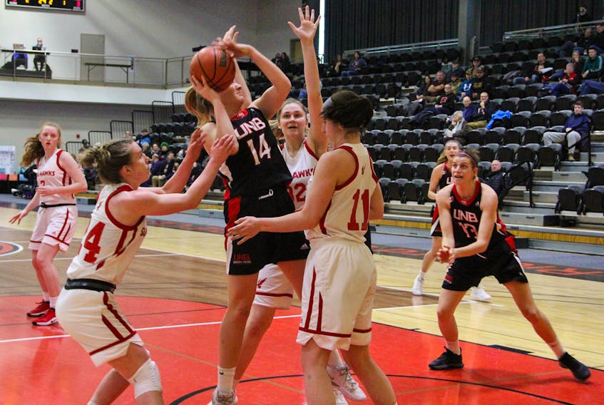 Grace Simpson of the University of New Brunswick Reds finds herself surrounded by Memorial Sea-Hawks players Cameron Longley (11), Gabrielle Roche (32) and Sammi Deakin-Sharpe (24) during AUS women’s basketball play Sunday in Fredericton, N.B. — Alex Dascalu/UNB Athletics
