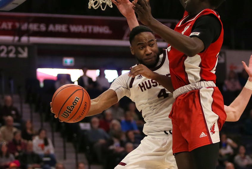 Saint Mary's Huskies guard Johneil Johnson dishes the ball off against the defence of Deng Ring of the Memorial Sea-Hawks during AUS Final 6 quarter-final action at Scotiabank Centre on Friday.  TIM KROCHAK / The Chronicle Herald 