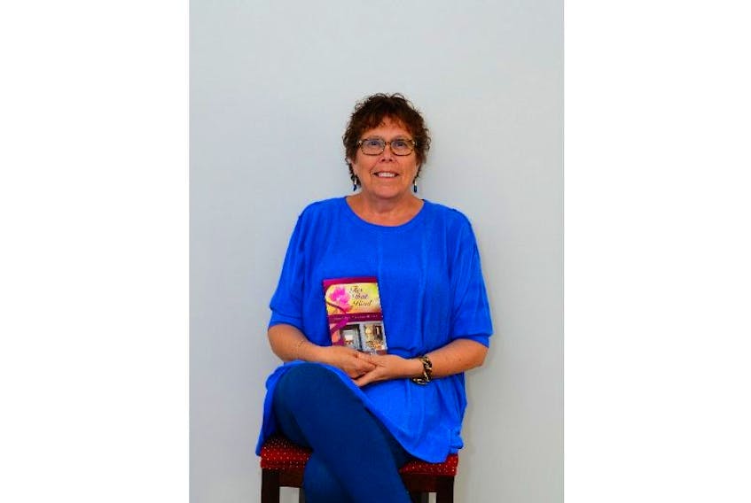 <p>L.P. Suzanne Atkinson holds up a copy of her latest book.  Atkinson released a creative non-fiction book in 2013.  Now she is releasing her first novel following six decades of the life of a professor at a small town university.</p>