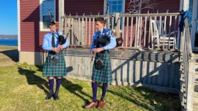 From left, Cameron MacNeil, 14, and his brother Aidan MacNeil, 16, perform "Amazing Grace" outside their home in Christmas Island, Friday morning, as a tribute to the Portapique shooting victims. The MacNeils are members of the Cape Breton University Pipe Band. CONTRIBUTED