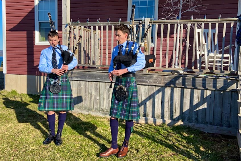 From left, Cameron MacNeil, 14, and his brother Aidan MacNeil, 16, perform "Amazing Grace" outside their home in Christmas Island, Friday morning, as a tribute to the Portapique shooting victims. The MacNeils are members of the Cape Breton University Pipe Band. CONTRIBUTED