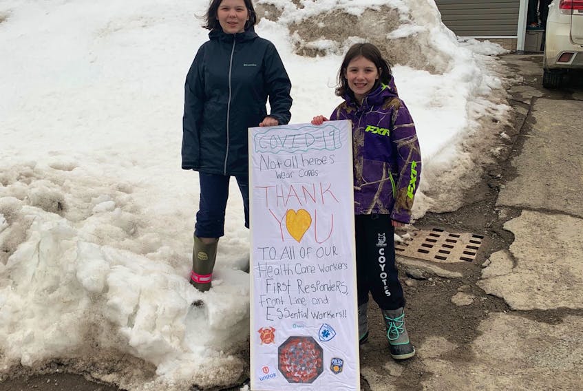 Baie Verte sisters Tahlia, left, and Claire Lewis wanted to show their support for essential workers so they made a sign. With a little help from their younger siblings, the pair stationed it at the end of their driveway on March 30. Contributed photo 