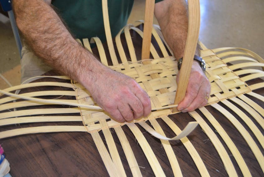 Assistant instructor Paul White weaves rattan through the stakes of the basket he’s making during a demonstration at the exhibit/open house of the Selkirk Millennium Seniors Club in Belfast this past Tuesday. SALLY COLE/THE GUARDIAN