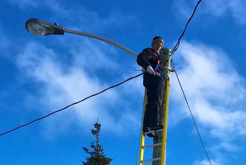 Jeremy Decker repairs an existing light at the Airport Nordic Ski Club