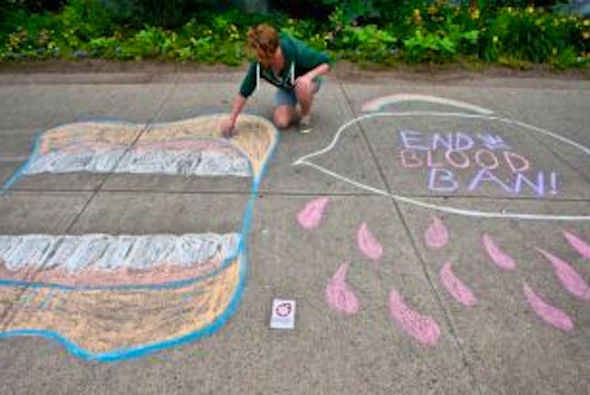 ['Sean MacIssac finishes up a section of a chalk protest at the Halifax Public Library.']