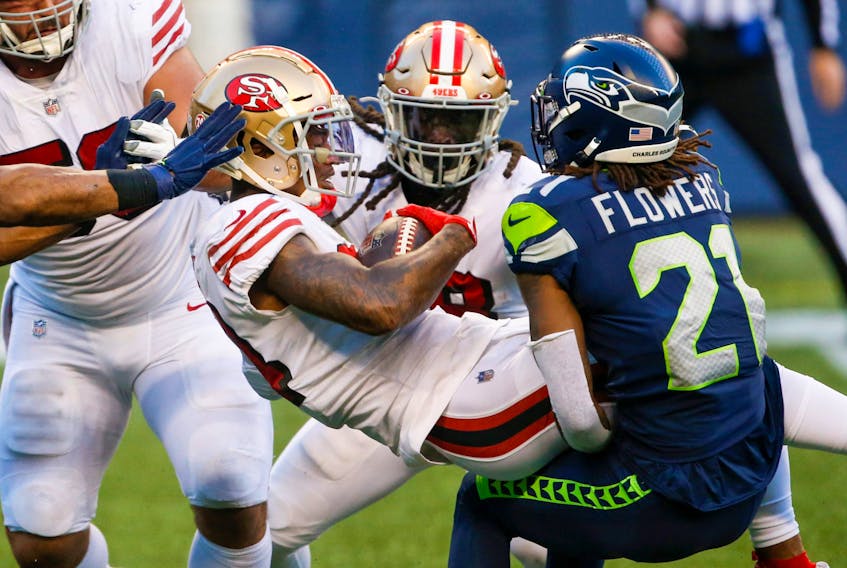 49ers wide receiver Kendrick Bourne (centre) is tackled by Seahawks’ Tre Flowers during Week 8 in Seattle. The status of Sunday’s San Francisco-Green Bay game is in question after Bourne reportedly tested positive for COVID-19. 