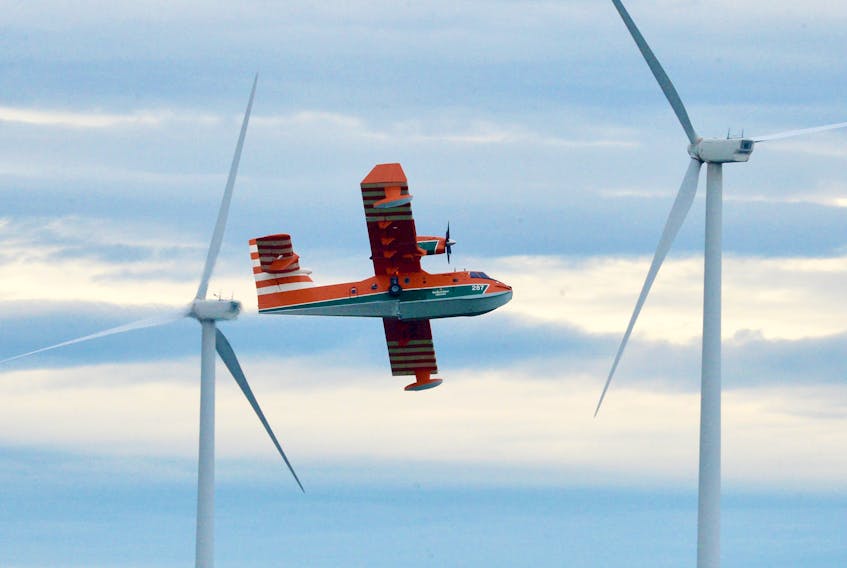A waterbomber passes wind turbines near Fermeuse Thursday afternoon while fighting a forest fire near the community. 