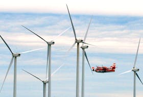 A waterbomber flies past wind turbines while fighting a forest fire near Fermeuse, N.L., Thursday evening.