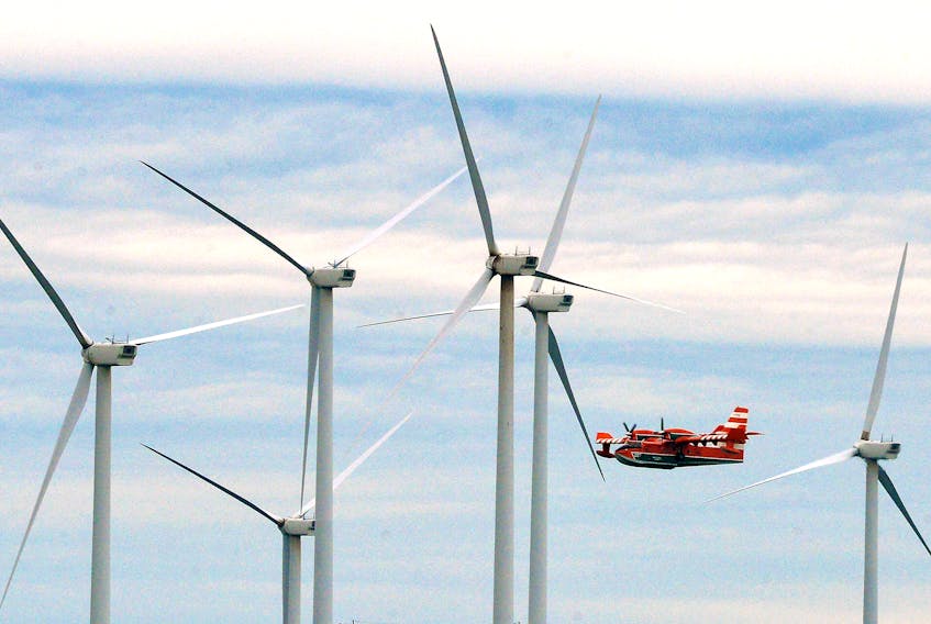 A waterbomber flies past wind turbines while fighting a forest fire near Fermeuse, N.L., Thursday evening.