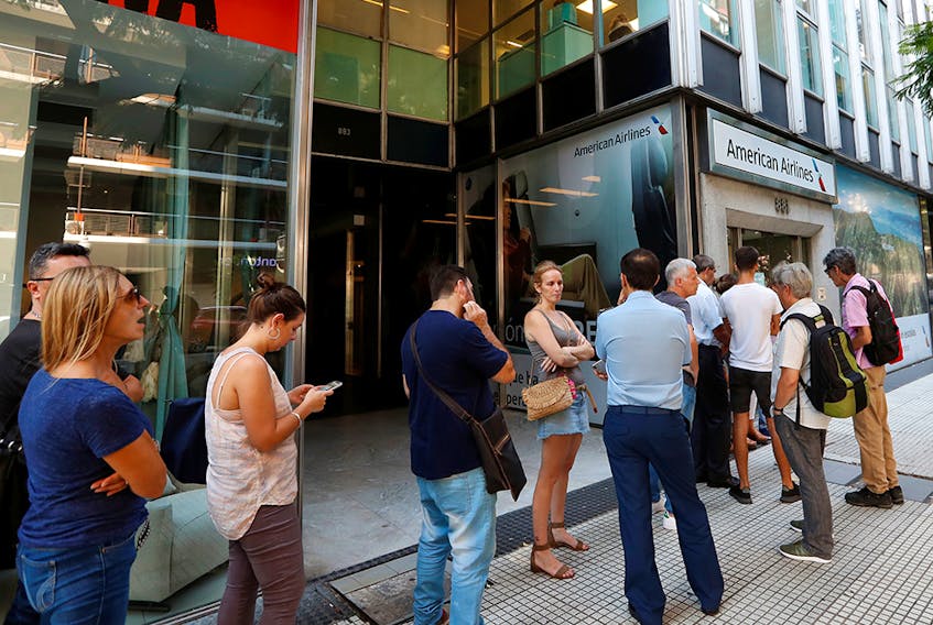 Travellers queue outside the American Airlines offices in Buenos Aires to change their flights due to the coronavirus outbreak on Friday, March 13, 2020. 