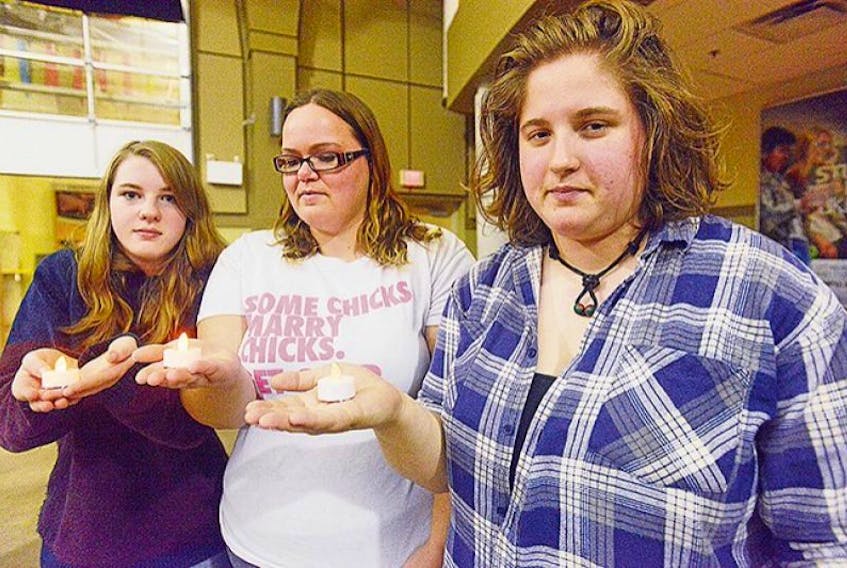 From left, Nicole Mann, Elyse Cottrell and Emily Horner hold symbolic flames in memory and support of all people who have died or suffer from homophobia and bullying. They were guest presenters at the fourth annual candlelight vigil hosted by University of Prince Edward Island Rainbow Alliance on the campus Thursday.