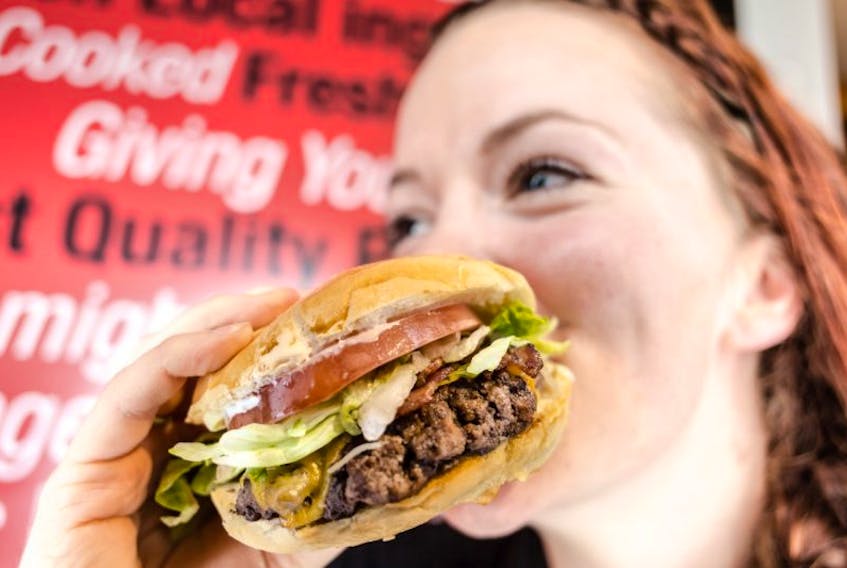 <p>Jonny’s Cookhouse and Ice Cream Shop employee Nikki Latta takes a bite out of a juicy burger prepared in the Berwick-based restaurant’s kitchen. Jonny’s is part of the inaugural Burger Wars this month with its “Full of Baloney” bacon cheeseburger.</p>