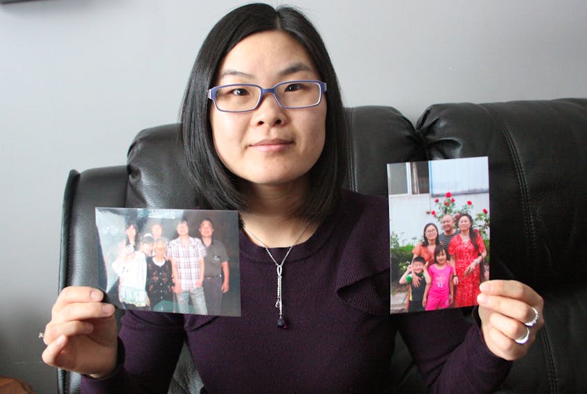 Stellar Spencer, a native of Wuhan, China, where COVID-19 was first identified late last year, holds a pair of family photographs. Spencer’s mother and father, who still live in the city, have been in lockdown in their home since January. PAUL HERRIDGE/THE SOUTHERN GAZETTE