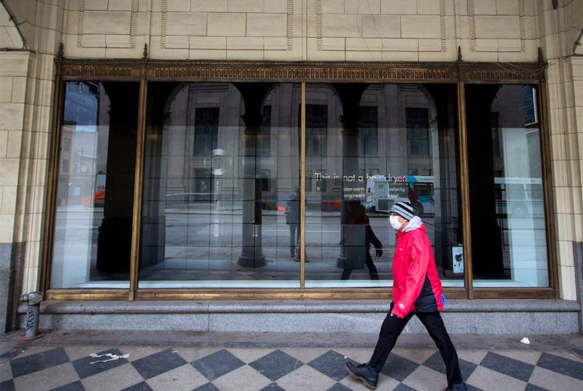  A man wears a mask as he walks past an empty display window at the downtown Calgary Hudson’s Bay on Monday, May 11, 2020.