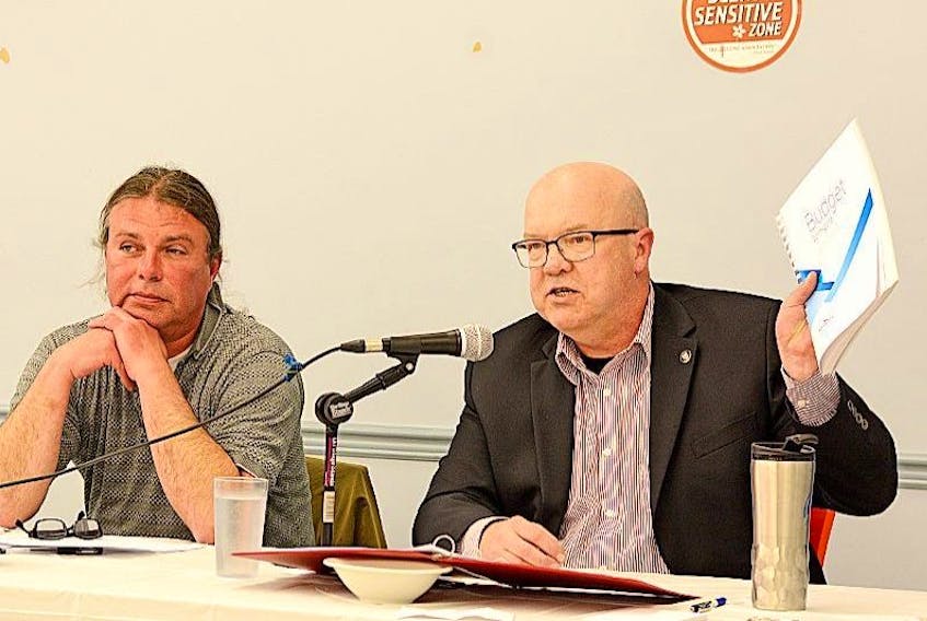 Independent candidate Richard Plett looks on as Cumberland North Liberal candidate Terry Farrell holds up a copy of the provincial budget while making a point at Tuesday’s Amherst and Area Chamber of Commerce candidates forum.