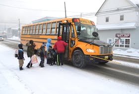 Volunteers Al Crawley, right, and his partner Kelly Brown assist students getting on the school bus at a Cape Breton-Victoria Regional Centre for Education stop on Victoria Road near Henry Street, Whitney Pier. The CBVRCE says this is one of the bus stops where they get the most complaints from bus drivers regarding motorists not heeding the red flashing light on the bus. Crawley said he sees several motorists ignoring the red lights on the school bus every week. Sharon Montgomery-Dupe/Cape Breton Post