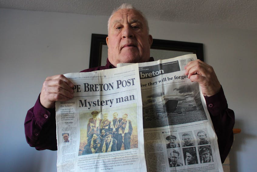 Sydney’s Hubert Mouland holds a copy of the Cape Breton Post from 2018 with an article relating to a search for Sydney native Reginald Bertram Smith whose bomber was shot down over Germany on Feb. 21, 1945. Mouland's cousin, front row-far left, Hubert James Mouland, is also in the photo. He was just 19 when his bomber crashed in Germany a month earlier in 1945.  GREG MCNEIL/CAPE BRETON POST