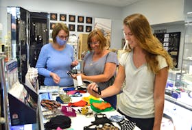 Sheila McCormick, left, manager of Emerald Isle on Welton Street in Sydney, shows customers Brenda Boutilier, centre, of Glace Bay, and her daughter Ashley Boutilier, an emergency room nurse in Halifax, some of their many non-medical reusable/washable face masks on hand. SHARON MONTGOMERY-DUPE/CAPE BRETON POST