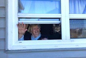 Louise MacNeil of New Waterford and her cat Cilo, waving to daughter Donna Ferguson of Gardiner Mines. Ferguson said the separation has been tough throughout the COVID-19 crisis as she never went anywhere without her mother. Sunday plans for Mother’s Day include leaving a pizza on the steps along with their regular window chats. Contributed.