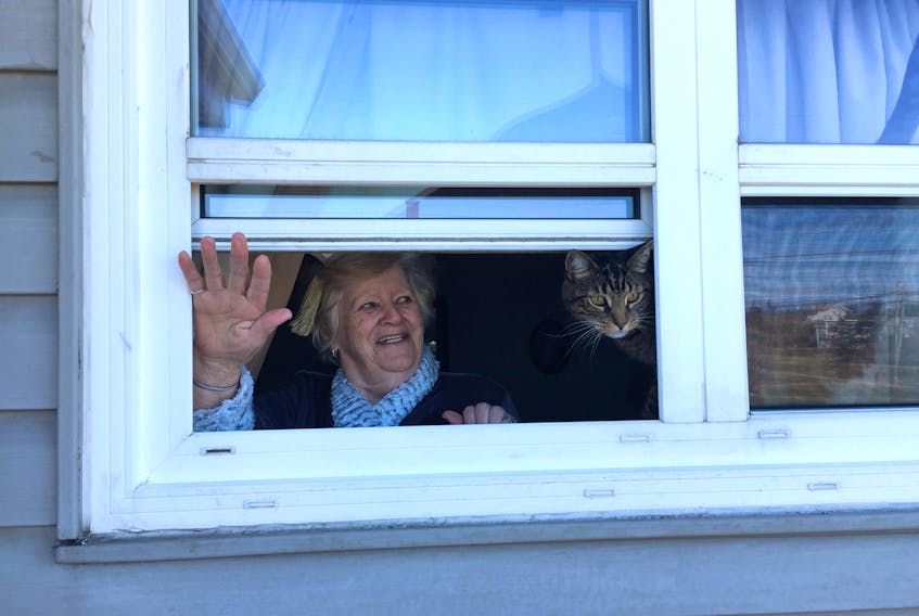 Louise MacNeil of New Waterford and her cat Cilo, waving to daughter Donna Ferguson of Gardiner Mines. Ferguson said the separation has been tough throughout the COVID-19 crisis as she never went anywhere without her mother. Sunday plans for Mother’s Day include leaving a pizza on the steps along with their regular window chats. Contributed.