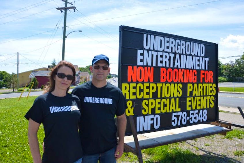 Stella Robinson, left, and Rob Smith stand in front of their promotional sign for Rob’s Underground Entertainment, located at 2 Elliot St. in Sydney Mines. The new venue will feature live bands on Friday nights and turn into a community hall for children’s dances on Saturday evenings. The official opening for the venue is set for Friday.