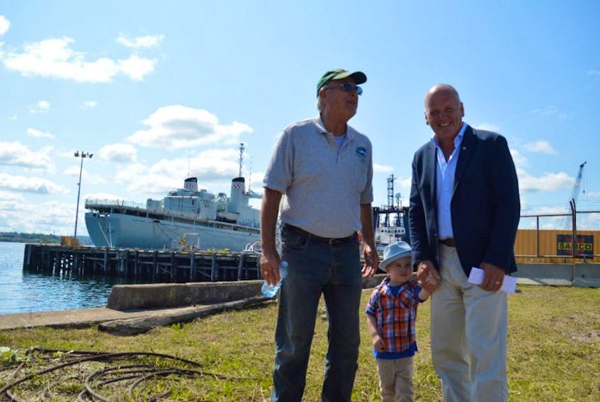 Wayne Elliott, director of business development with Marine Recycling Corp, left, and Sydney-Victoria MP announced Friday that the former Canadian navy ship HMCS Preserver will be dismantled at Sydport Industrial Park as part of a $12.6 million federal contract. Eyking brought along his grandson Ryker Rideout, who is a fan of ships.