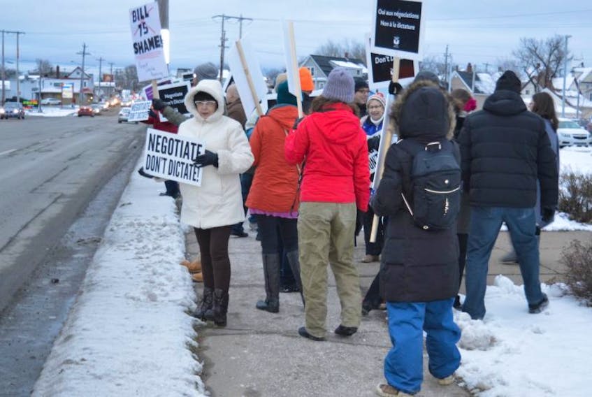 People wave signs at passing motorists along Prince Street in front of the Provincial Building on Monday. About 600 people lined both sides of the street for a rally in support of teachers embroiled in a labour dispute with the province.