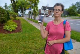 Sarah Morrison holds up her cell phone where she has saved text messages from Bell Aliant confirming they said they were waiting on a part to fix issues in the area and that she had informed them of 10 residences with no landline service.