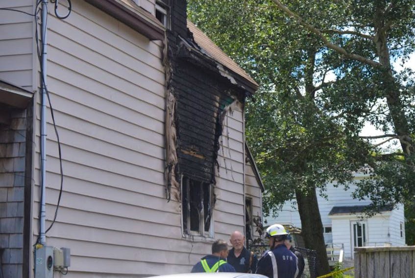 Fire marshals and police investigators probe the scene of a Sydney Mines house fire on Wednesday. The blaze at the Oxford Avenue home happened Aug. 4, three weeks after a woman living at the address was arrested and charged with second-degree murder in connection with a vehicle-pedestrian incident on the same street.