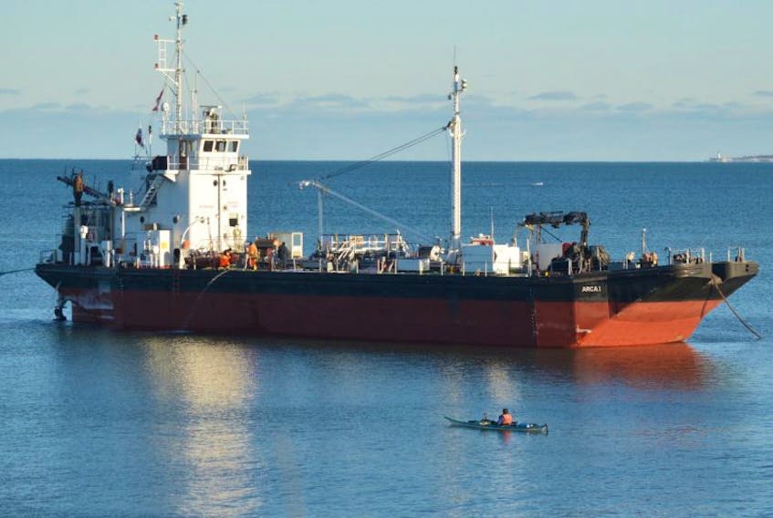 A lone kayaker checks out the MV Arca 1, a 53-metre tanker than ran aground in the shallows below the cliffs of Little Pond, 10 km northwest of the mouth of Sydney Harbour, last Sunday. Workers can be seen preparing the ship prior to an attempt to tow the vessel back to sea during high tide early Tuesday evening. However, the tanker remains where it washed up after officials postponed the salvage job.
