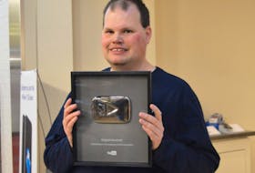 Amateur weatherman and Internet celebrity Frankie MacDonald shows off the Silver Play Button award he received from YouTube in recognition of surpassing more than 100,000 subscribers to his “dogsandwolves” channel.