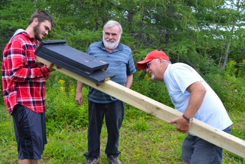 Jarrett Byrne, from left, a summer worker with the Port Morien Wildlife Association, prepares a bat houses to be mounted with help from John Kennedy, association secretary, and Stan Peach, treasurer. The wildlife association received a grant for the project to help monitor the health of the Cape Breton bat population.