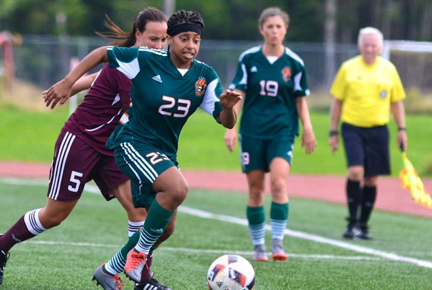 Cape Breton University striker Keona Simmonds head down the pitch while being pursued by Saint Mary’s University defender Jani Marchand-Lemire during the Capers 6-0 season-opening win over the Huskies on Saturday at the CBU field. The Capers number 19, Becky Hanna, looks on.