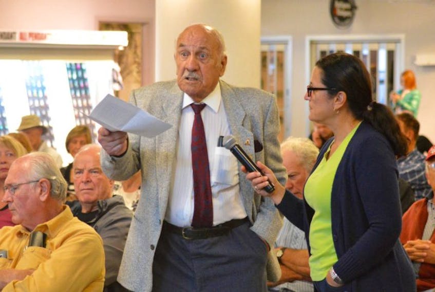 Ninety-five-year-old Charlie Palmer makes a point during his time on the microphone, held by Scotia Rail Development Society board member Patricia Morrison, during the organization’s public meeting Sunday at the Joan Harriss Cruise Pavilion in Sydney.