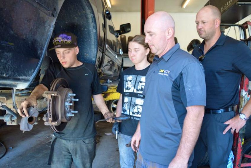 Jacob Campbell of Glace Bay, from left, works on brakes at OK Tire on Reserve Street, Glace Bay, as Neil Thomas of Glace Bay, Troy Baldwin, manager of OK Tire, and Greg Connell, co-ordinator of the YMCA Youth Leadership Program, look on. Campbell and Thomas have gained work experience through the youth program.