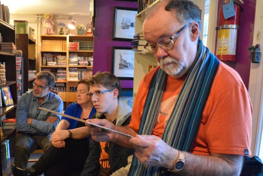 Joe Sampson studies the cover of “Feats Don't Fail Me Now,” while Edwin MacLellan, from left, Deborah Long and Sam MacDougall listen to the album during a Vinyl Sidings meeting at Ed’s Books and More on Charlotte Street in Sydney