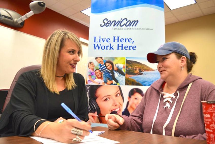 Dani Mombourquette, left, a recruiter for ServiCom in Sydney, chats with Sherry Lambert of Glace Bay during a job fair hosted by the YMCA of Cape Breton Nova Scotia Works Employment Services Centre on Reserve Street in Glace Bay on Tuesday. ServiCom plans to hire 50-100 more people by the end of the year.