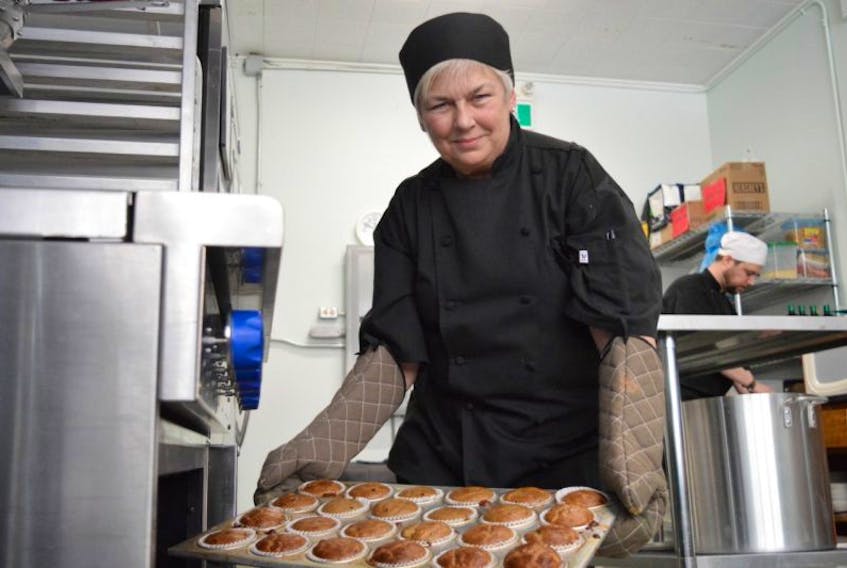 Susan Hawes, prep chef for meals on wheels, is shown taking homemade muffins out of the oven on Tuesday morning. Hawes volunteers her time with the program, working roughly 20 hours a week.