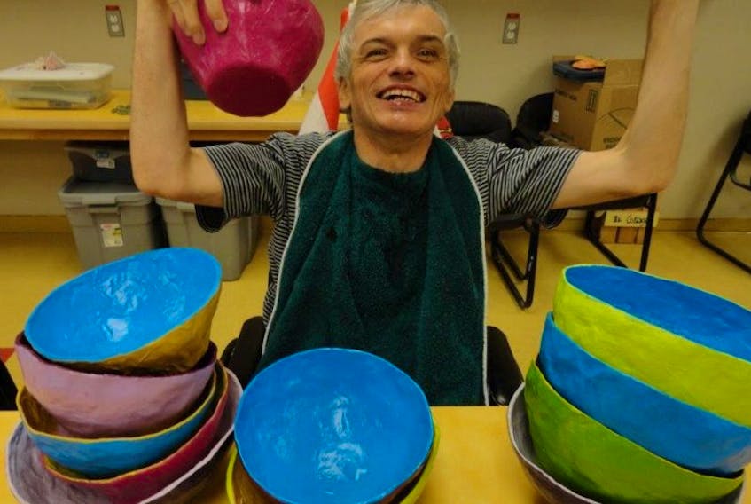 Buddy Payne holds up some of the colourful bowls that he creates at L’Arche Cape Breton.