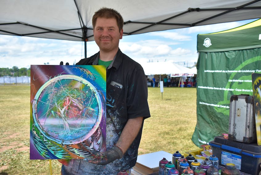 Nathan Salmon holds one of his most requested spray paint pieces, which features a dream catcher. Each painting he does is by request and Salmon said his favourite things to paint are when customers come up with a random idea.