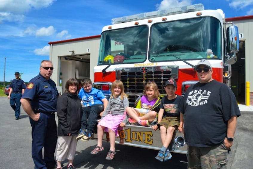 Members of the community, young and old, were in attendance for the grand opening of the new Sydney fire station on Victoria Road. Seen are some of the people in attendance for the opening, sitting on the front of a fire truck, from left, Stephen MacVicar, acting captain, April Bond, Kevin Bond, Shirley Bond, Monica Henick, Max MacDonald and David MacDonald.