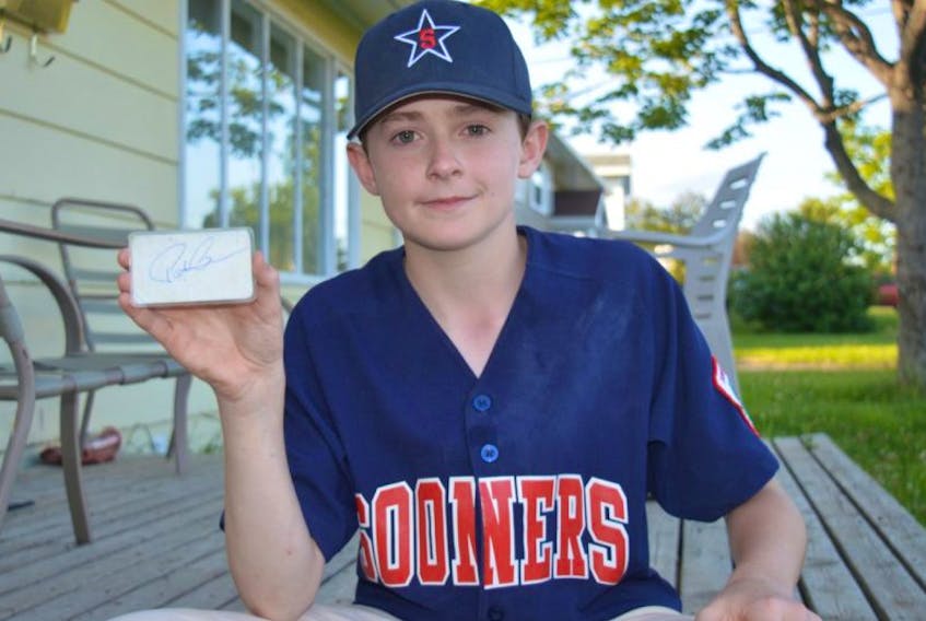 Matthew (Bug) MacDonald of Coxheath is shown with a laminated businesses card autographed by NHL hall of fame coach Pat Burns that was owned by MacDonald’s late grandfather, Donnie MacEachern. The 13-year-old member of the Sydney Sooners junior team believes his grandfather was with him and his teammates in their 8-7 win over the Glace Bay Logistec Miners on Sunday as they claimed a provincial championship.