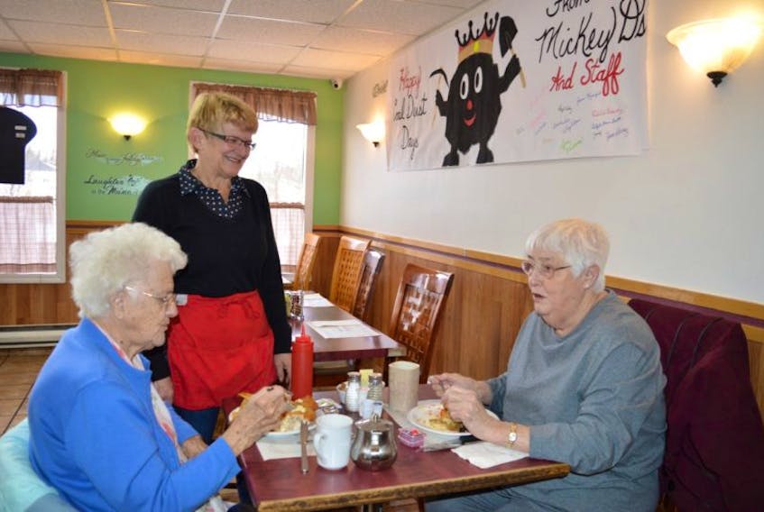 Joanne Mossop, standing, owner of Mickey D’s Restaurant on King Street, New Waterford, chats with Rita MacEachern, left, and Brenda MacKenzie, both of New Waterford, at the restaurant on Tuesday. Mossop said the cancellation of the 36th annual Coal Bowl Classic will hurt businesses in the community but overall it’s the loss of the 36-year tradition that is more concerning.