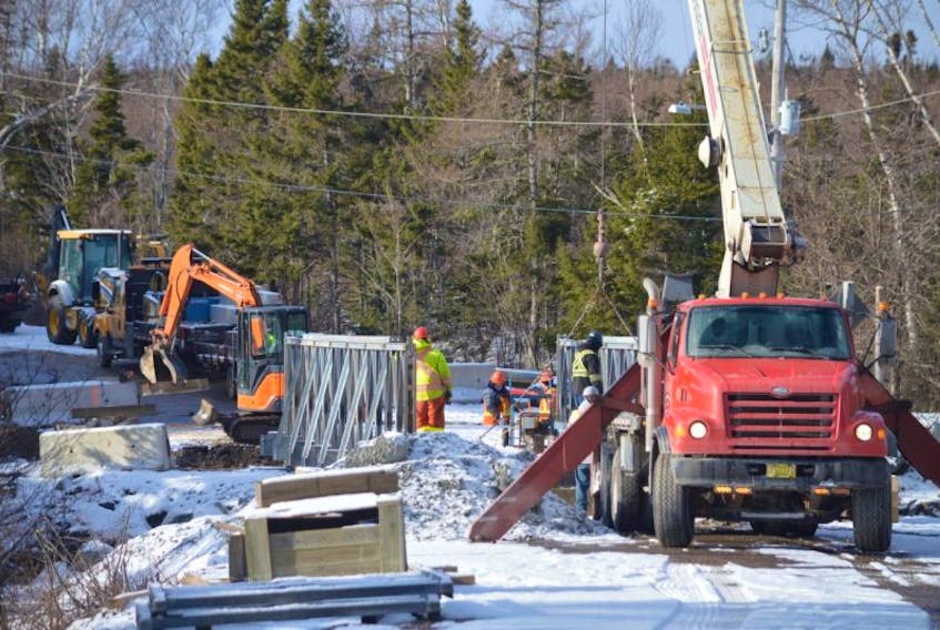Crews with the provincial transportation department are seen working to install a new temporary bridge on Hornes Road in Mira Gut on Tuesday. The bridge has been closed since Oct. 10 after it was destroyed by floodwaters.