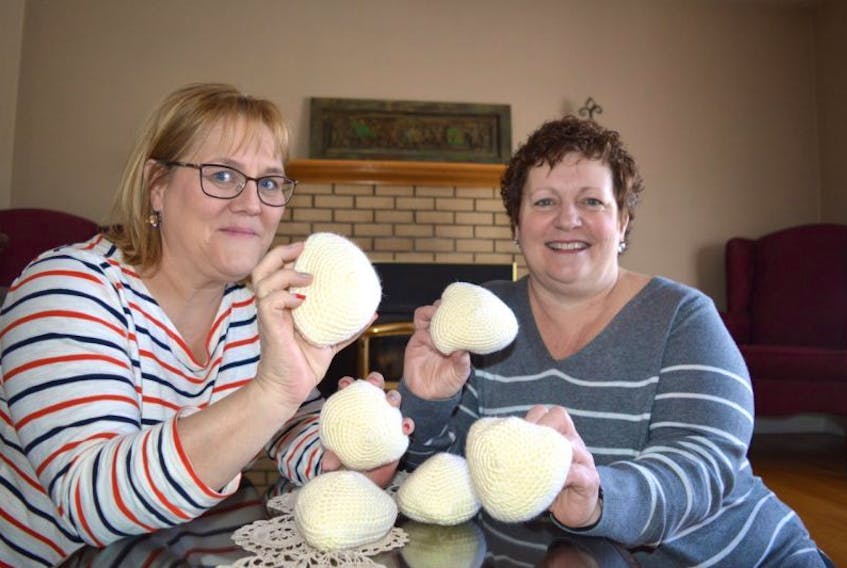 Heather McNeil, left, a member of Island Breast Friends, and Joe Ann MacKinnon of River Ryan, both breast cancer survivors, hold up knitted knockers which are an option for anyone needing a prosthesis. Island Breast Friends is looking for people to help knit the knitted knockers for breast cancer survivors.