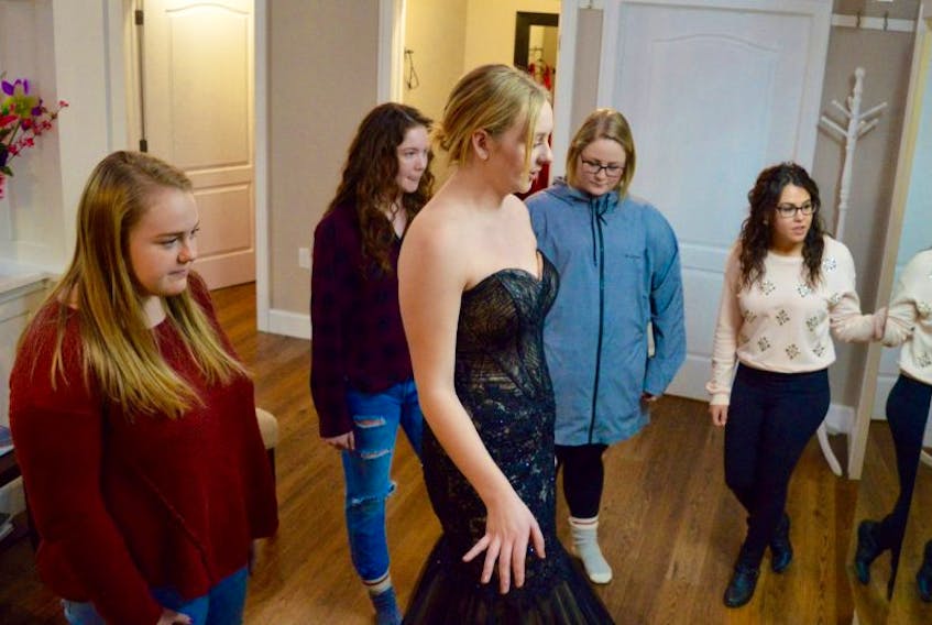 Grade 12 Riverview High School student Danielle Pyke, centre foreground, tries on a prom gown, while from left, classmates Meagan Campbell, Brooklyn Etheridge and Haely Langlois look on with Timeless Moments’ Brittany Woodworth. The dress shop owner plans to help organize proms for five area high schools should the June events be cancelled due to the ongoing work-to-rule campaign by Nova Scotia teachers.