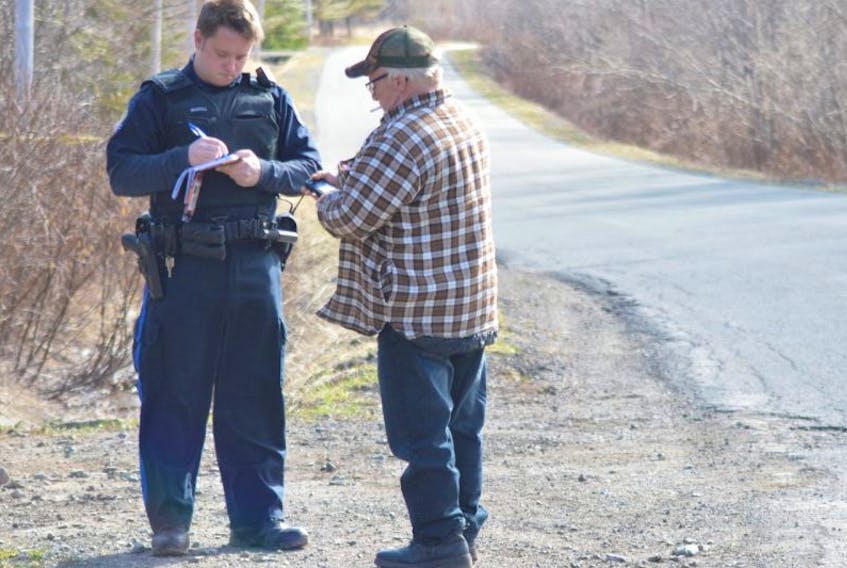Ricky McNeil, right, talks to an unidentified member of the Cape Breton Regional Police Service on Tuesday near the property owned by his son Richard McNeil and his son’s common-law wife, SarahBeth Forbes. On Wednesday Richard McNeil was in Sydney court charged with the first-degree murder of Forbes.
