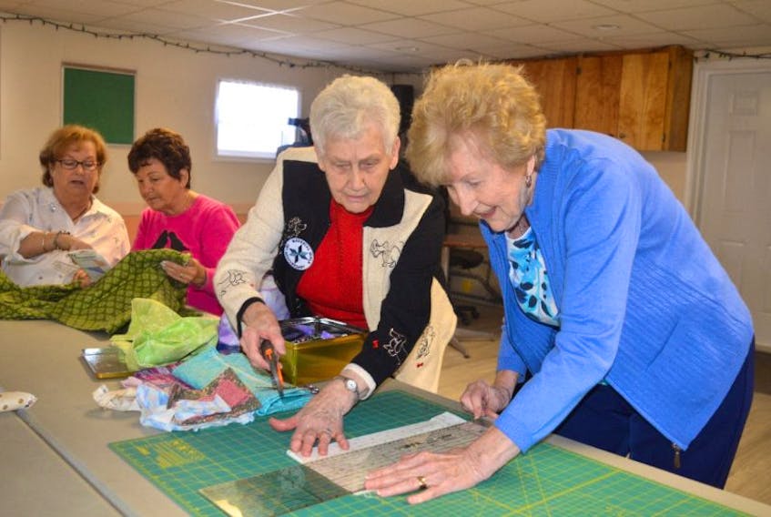 Annunciata Rogez, right, a member of the Material Girls quilting class gets assistance from instructor Mariette Pond, while, from left, Mary MacIntyre and Dolores Doucette work on projects, during a class Wednesday at the Reserve Mines Seniors and Pensioners Hall.  The Material Girls are inviting the public to their 15th anniversary celebration Sunday from 2-4 p.m. at the hall which will include a display of their quilts.